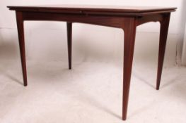 A stunning 1970's Danish teak dining table being raised on turned legs shaped rectangular table top