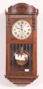 A 1930's oak cased wall clock with bevelled glass pendulum window,