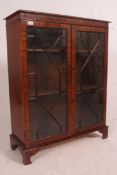 A Regency style mahogany bookcase display cabinet raised on bracket feet with twin astragal glazed