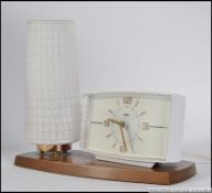 A retro 20th century Metamec electric alarm clock lamp combination, being raised on a teak base.