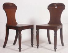 A pair of Georgian early 19th century mahogany hall chairs of armorial form,