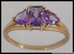 A hallmarked 9ct gold dress ring with triple stone Amethyst in a prong setting with raised pierced