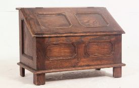 A 1920's oak Jacobean revival coal / log box having geometric fielded panels with hinged top all