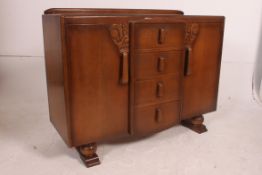 A 1930's Art Deco oak sideboard having a central bank of drawers with cupboards either side.