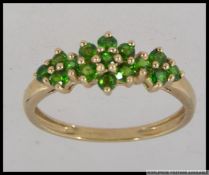 A hallmarked 9ct gold dress ring with round cut peridot in a triple cluster setting. Size V.