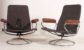 A pair of retro swivel armchairs in the manner of Ekornes dating to the 1970's having leather elbow