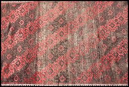 An early 20th century handwoven Persian rug with red ground - black wave design to centre and wavey