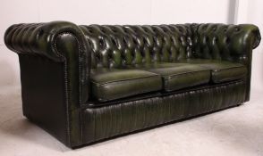 A green leather three seater Chesterfield sofa.