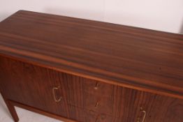 A Danish rosewood 1960's sideboard raised on thin tapering chamfered edge legs with a central bank