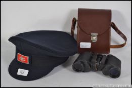 A pair of Carl Zeiss Jena Jenoptem 8 x 30 cased binoculars, along with an Intercity guardsman hat.