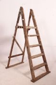 A vintage Industrial mid century wooden step ladder of medium proportion and a-frame construction.