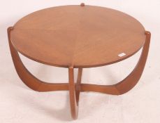A vintage mid century teak coffee table of circular construction with curled atomic style supports,