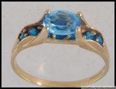 A hallmarked 9ct gold dress ring with central oval cut blue topaz with round cut blue topaz set in