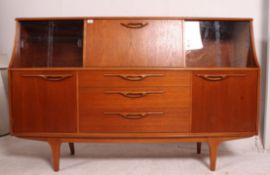 A 1970's G-Plan teak wood sideboard raised on turned legs with wide and upright body having