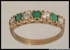 A hallmarked 9ct gold ring with green and clear stones in a cup setting. Hallmarked Sheffield.
