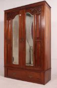 An Edwardian mahogany arts and crafts double wardrobe having plinth base with drawer and double
