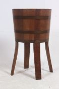 An early 20th century cooped brass and teak bound ice bucket - wine cooler being raised on squared