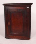 A 19th century oak corner cabinet raised on a plinth base with single door having shelved interior,