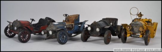 A collection of 4 tin plate vintage model cars to include red, blue, black and yellow cars.