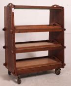 An Arts & Crafts oak 4 tier tray trolley in the Cotswold style raised on castors,