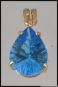 A large hallmarked 9ct gold pendant set with an pear cut blue stone in a prong setting.