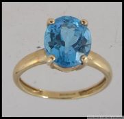 A hallmarked 9ct gold dress ring with large oval cut blue topaz in a prong setting. Size R.5.