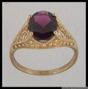 A hallmarked 9ct gold dress ring with large oval cut garnet in a prong setting with with filigree