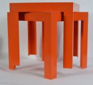 A pair of retro Kartell orange occasional tables of plastic form being raised on squared supports.