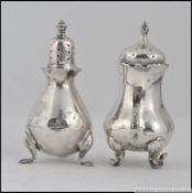 A silver hallmarked cruet set ( non matching ) of bulbous body each raised on splayed legs 70.
