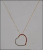 A 9ct gold pendant necklace with heart shaped pendant with rubies and diamonds in a channel setting.