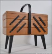 A 1950's retro / vintage metamorphic sewing box with metamorphic action being raised on ebonised