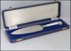 A cased silver hallmarked cake knife / server complete in the blue presentation case.