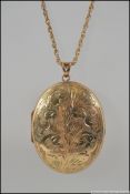 A large hallmarked 9ct gold locket with etched scroll decoration to front strung on a 9ct gold rope