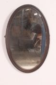 A large 19th century oval wall hanging mahogany framed mirror, having a bevel edged mirror panel.