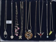 A collection of silver / white metal pendant necklaces, all displayed mounted on a velvet board.