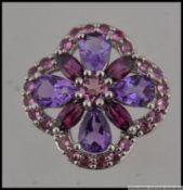 A hallmarked 9ct white gold gem set pendant set with pink and purple gem stones. Size 2cms.
