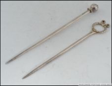 2 silver plated Tiffany & Co knitting needles, one with bow ribbon hoop end, the other with finial.