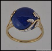 A hallmarked 9ct gold dress ring set with a large lapis lazuli cabouchon with entwined diamond set