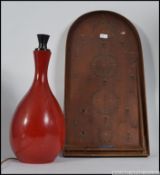 A vintage wooden Corinthium bagatelle board together with a red laquered table lamp.