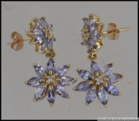 A pair of hallmarked 9ct gold drop earrings set with tanzanite and diamonds in a cluster flower