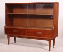 A retro 20th century teak wood display bookcase having two full length glass sliding doors over two