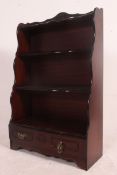 An antique style mahogany waterfall bookcase having shaped sides and graduating shelves with