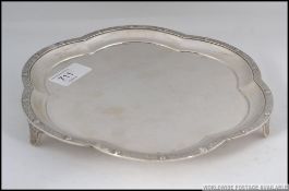 A silver hallmarked salver having unusual detailed in relief borders being raised on shaped legs