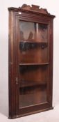 A large Victorian mahogany corner cabinet with full length glazed door having shelved interior and