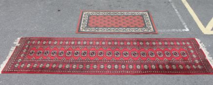 A 20th century handwoven Bokhara runner with central medallions on red ground together with another.