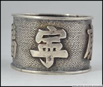 A chinese silver napkin ring in the manner of Wang Hing having large character marks to the banded