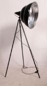A retro style Black Moon tripod standard lamp light raised on a tubular tripod stand,