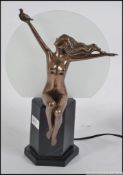 An art deco style table lamp, with a naked women sat upon a plinth holding aloft a dove .