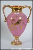 A large twin handled Victorian Staffordshire campana vase having pink ground with gilded details of