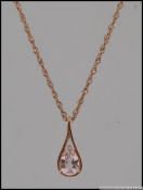 A 9ct rose gold pendant necklace strung with a drop pendant set with a pear cut morganite.